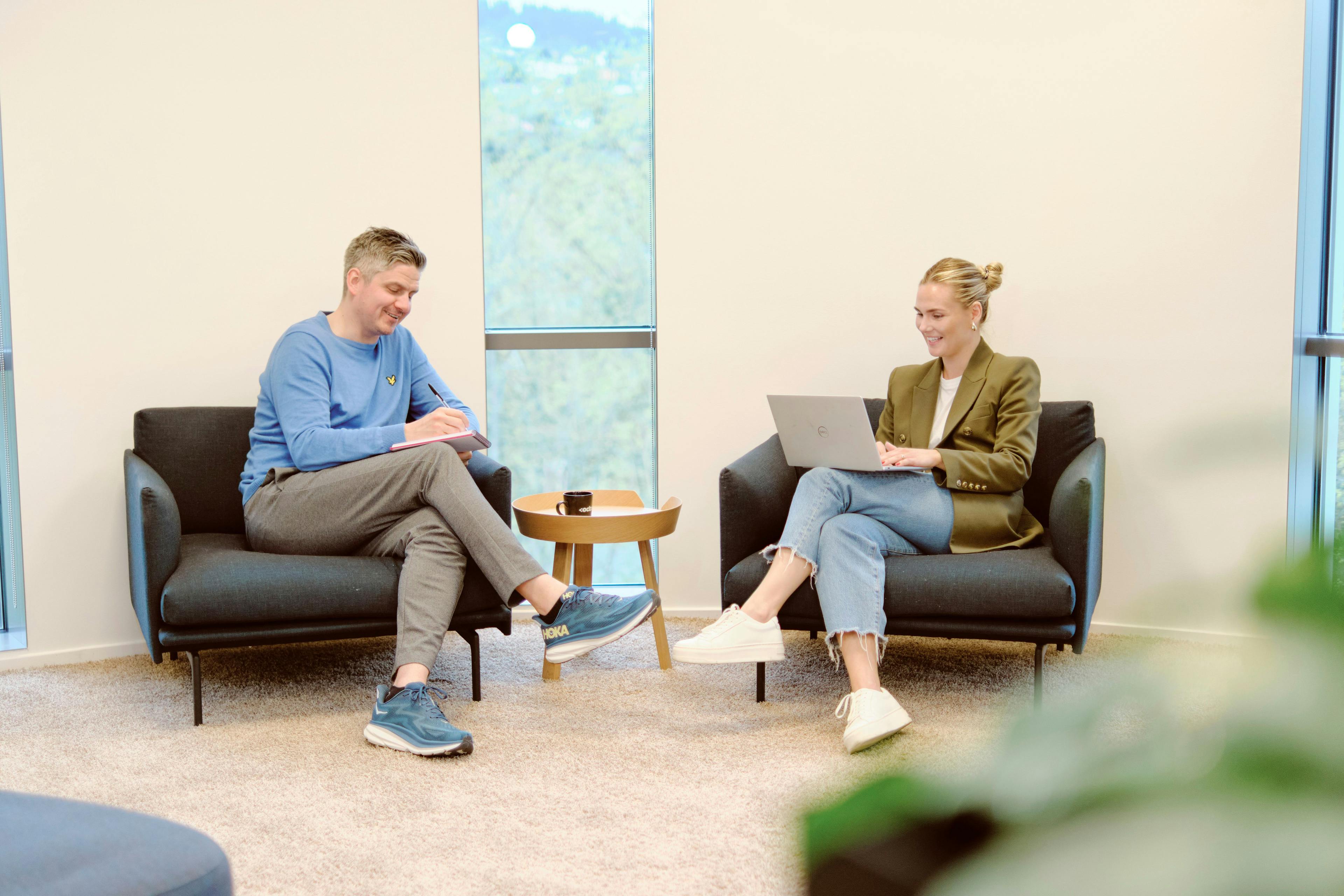 Bilde av to personer som sitter og snakker med hverandre på et kontor i Teknobyen